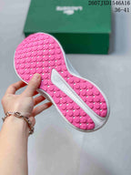 Pink patterned outsole of a white and pink sneaker, showing circular tread details.