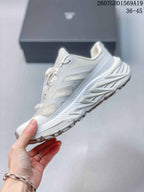 Side profile of the white sneaker showing mesh-like panels, structured overlays and a raised lugged sole.