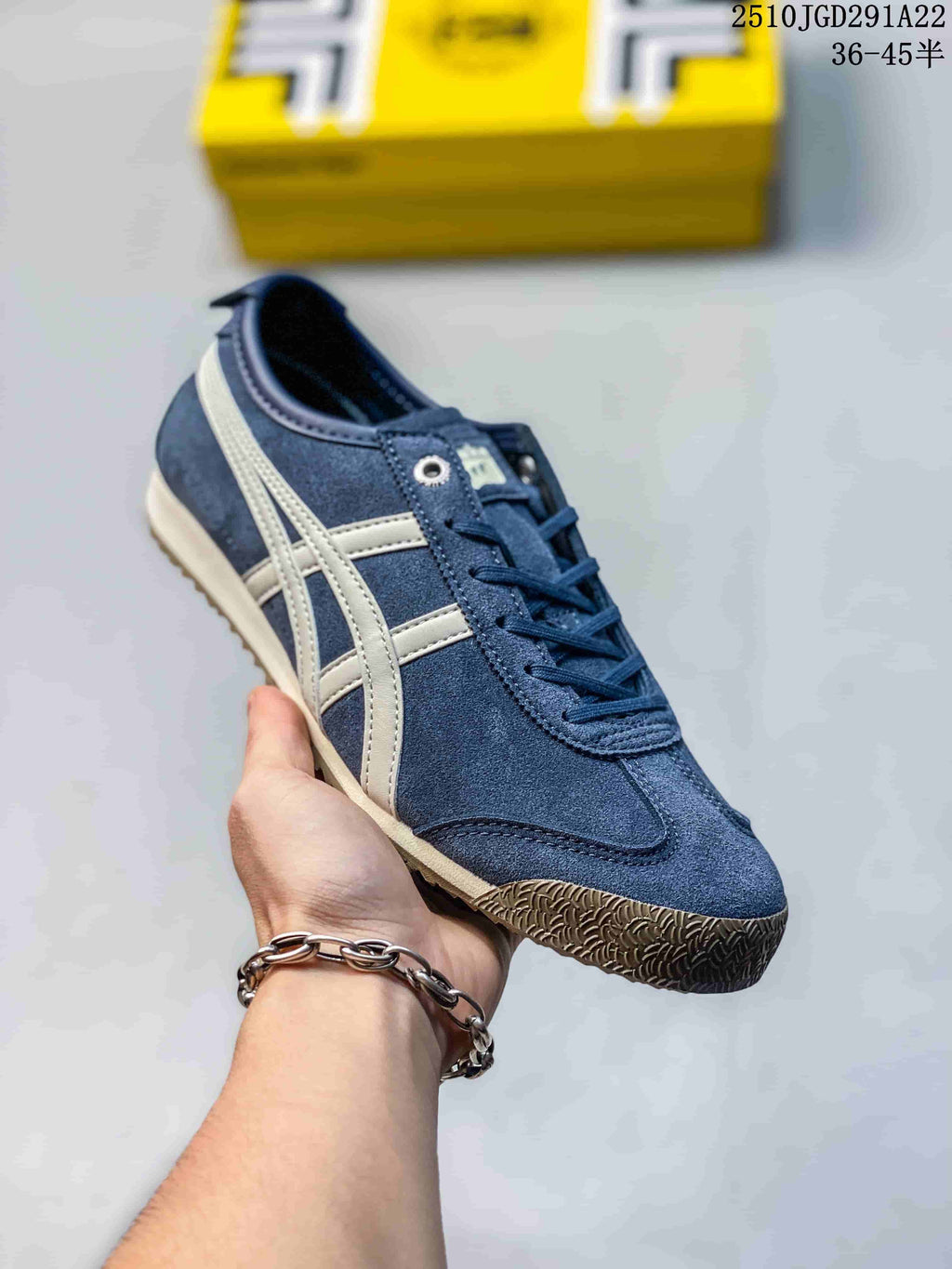 Navy blue Onitsuka Tiger sneaker held in hand, showing white contrast stripes and a textured brown outsole.