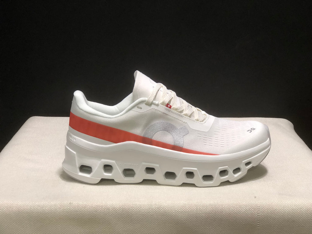Side view highlighting the white upper, coral stripe and open-detail outsole.