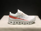 Side view highlighting the white upper, coral stripe and open-detail outsole.