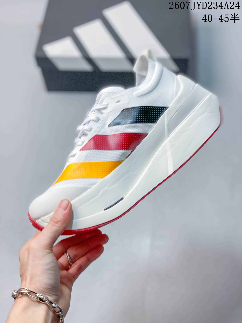 Side view of the white running shoe with black, red and yellow layered accents.