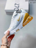 Side profile showing the white patterned upper, gold Swoosh, and translucent gold heel unit.