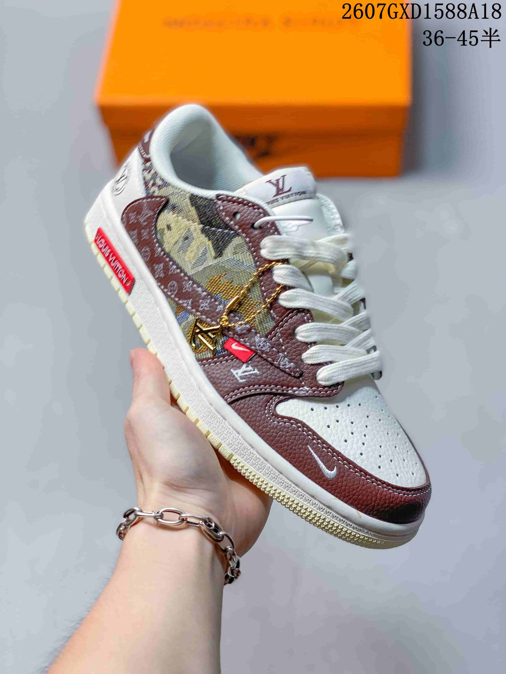 Angled side view of the sneaker showing brown overlays, a patterned monogram-like panel, decorative side attachments, and white laces.
