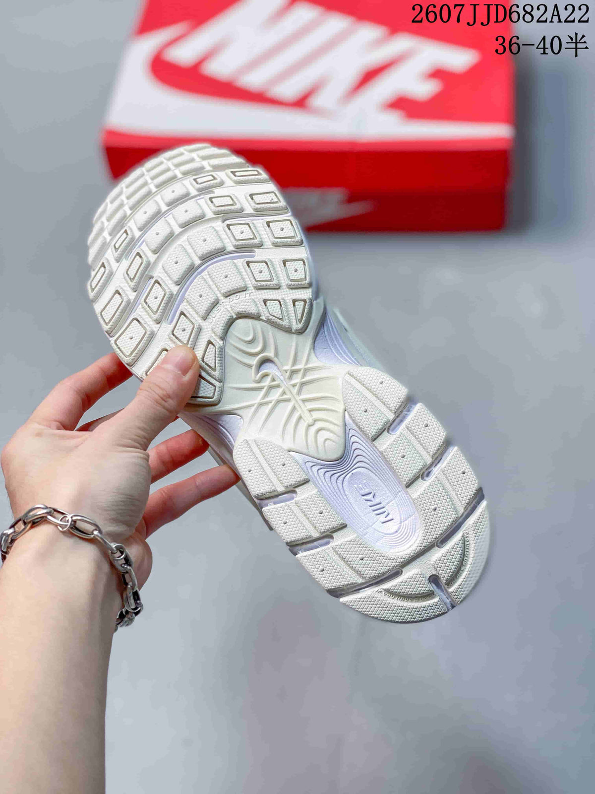 Underside view of a white Nike sneaker showing the segmented textured outsole and sculpted midsole.