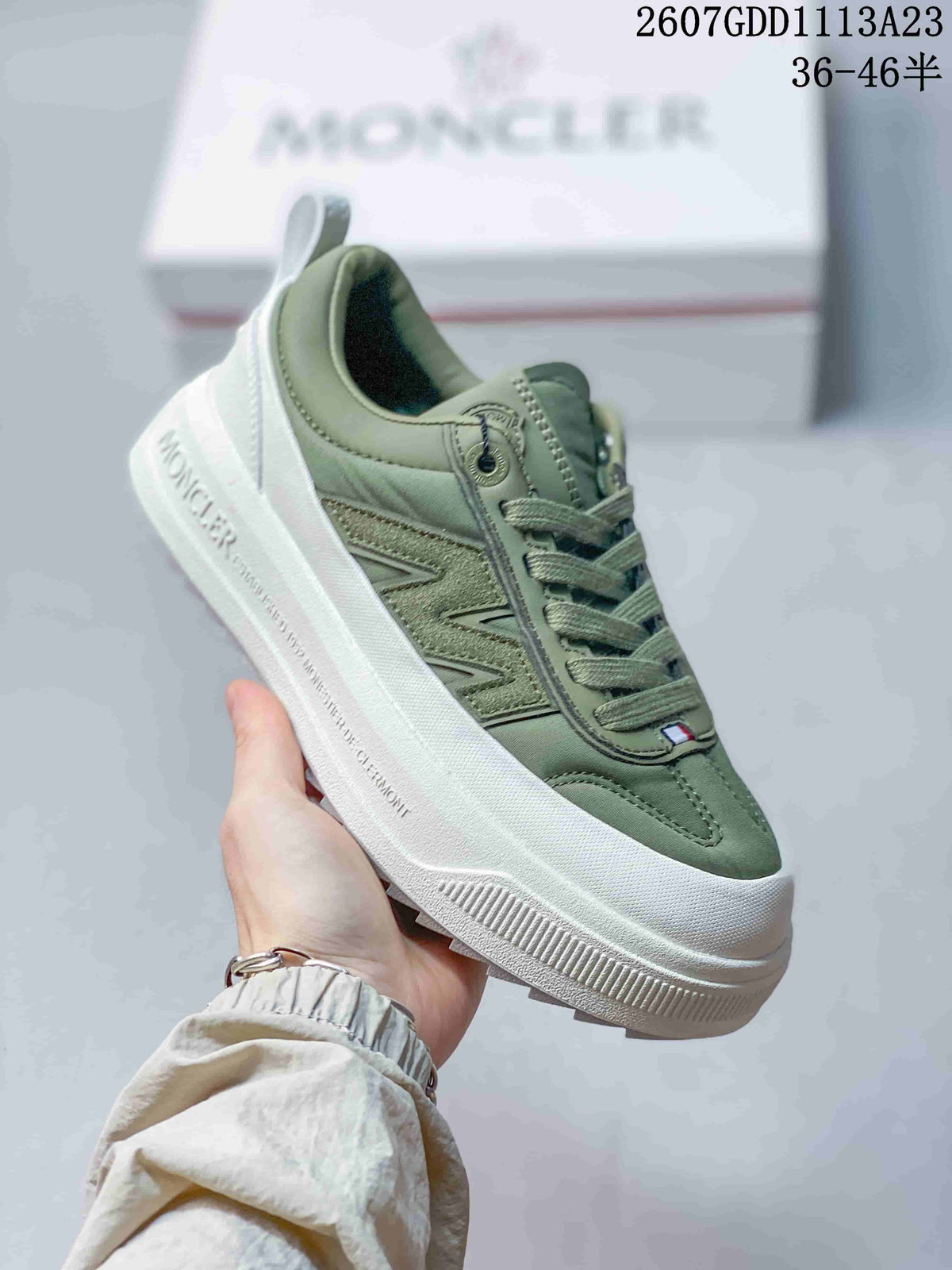 Side view of a muted green Moncler Pacey sneaker showing the contrast side panel, lace-up closure, and raised white sole.