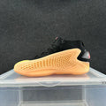 Black high-top sneaker with a bright orange honeycomb-patterned side panel and pink heel accent