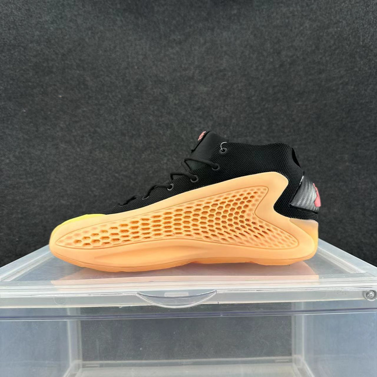 Black high-top sneaker with a bright orange honeycomb-patterned side panel and pink heel accent