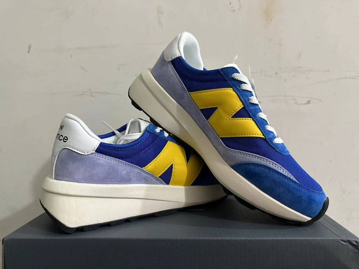 Pair of blue and yellow New Balance U370 sneakers shown from the side