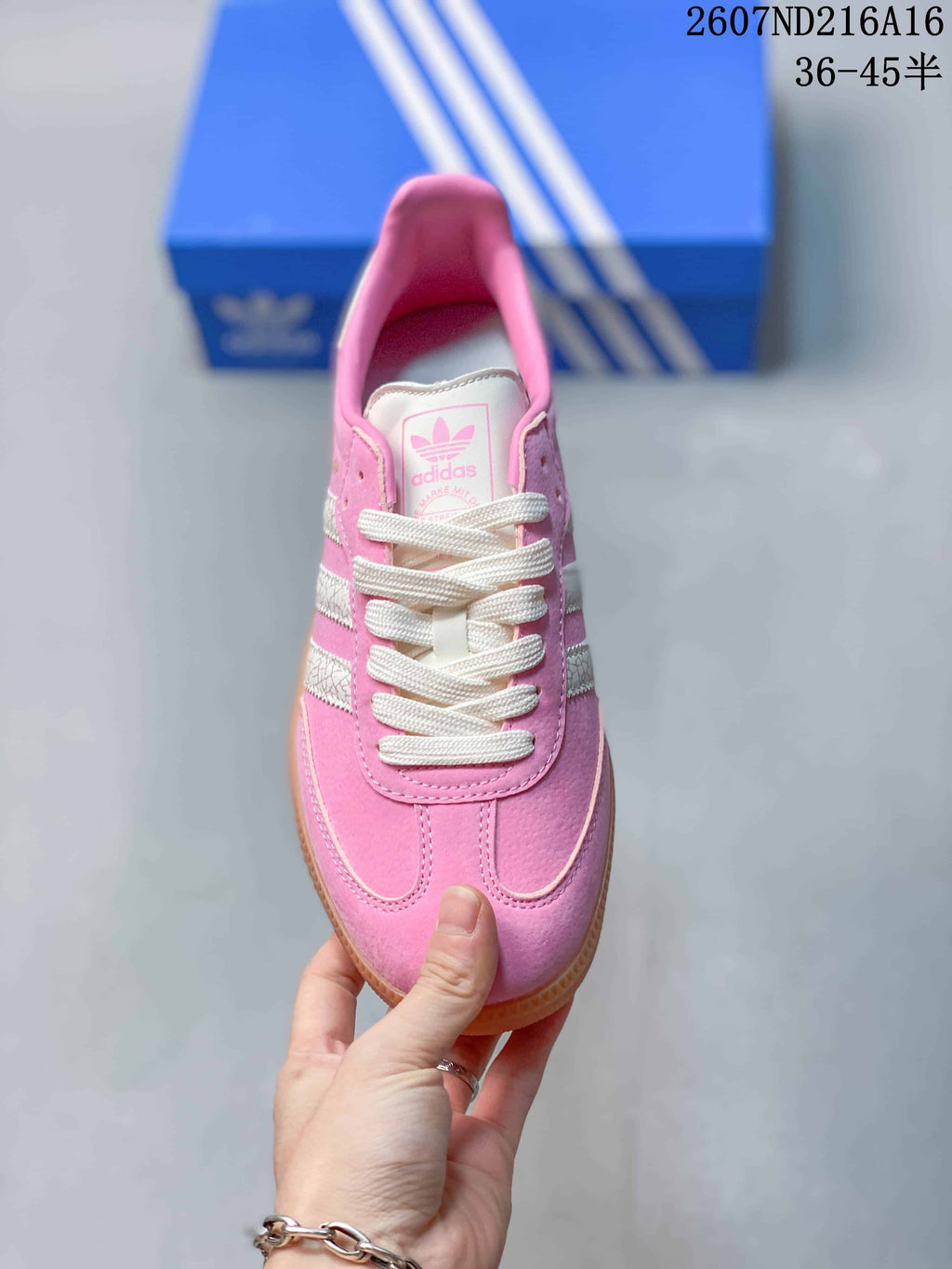 Top view of the pink and white sneaker showing the white laces, stitched toe detail and tongue branding.