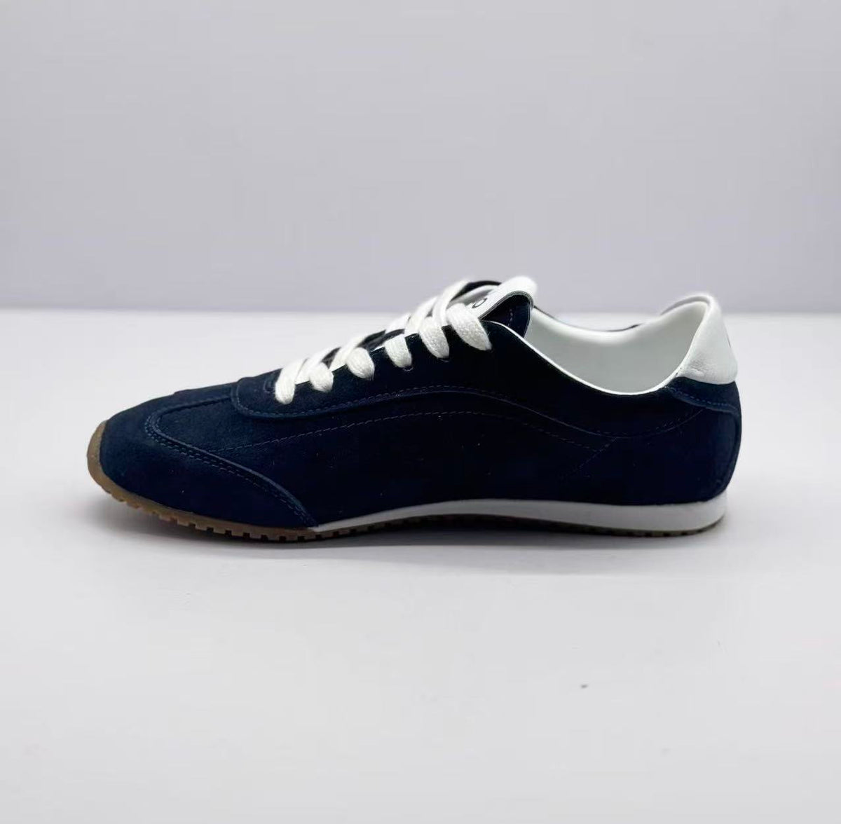 Side profile of the deep blue sneaker with stitched panels, white laces, and a gum-colored outsole.