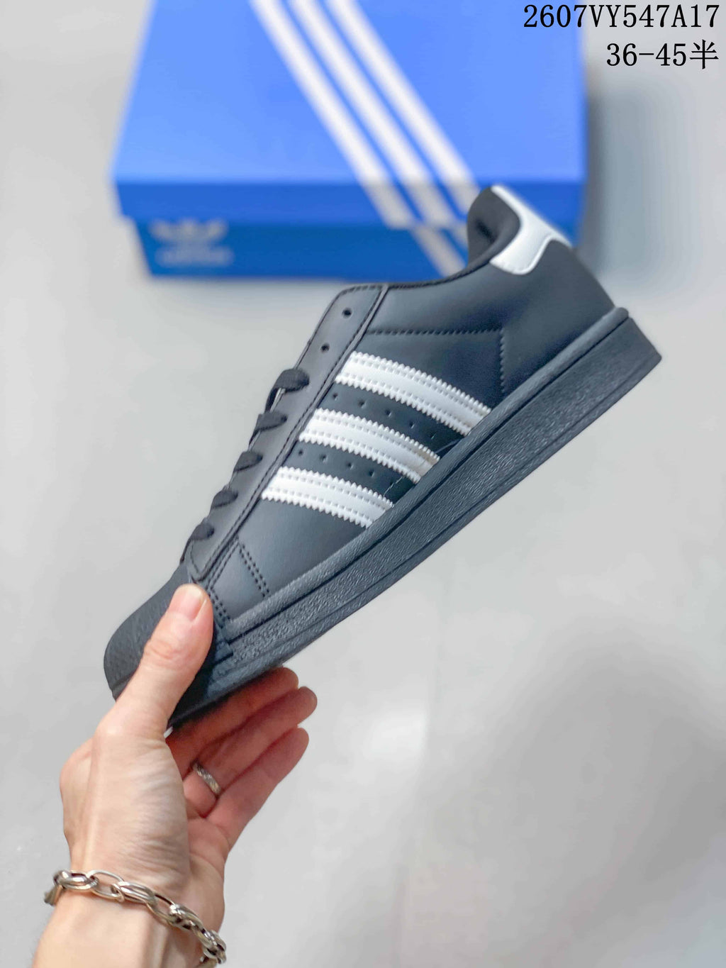 Side view of the black low-top sneaker with white three stripes, dark sole and white heel accent.