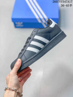 Side view of the black low-top sneaker with white three stripes, dark sole and white heel accent.