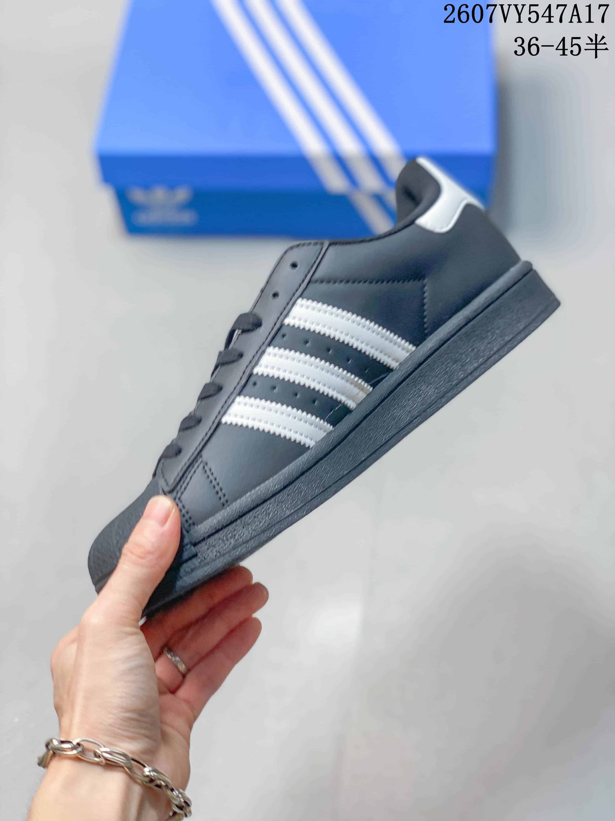 Side view of the black low-top sneaker with white three stripes, dark sole and white heel accent.
