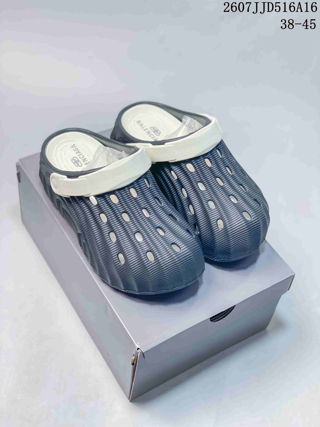 Navy and white perforated clogs displayed on a box, showing the rounded toe and contrasting straps.