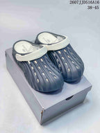 Navy and white perforated clogs displayed on a box, showing the rounded toe and contrasting straps.