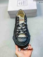 Top view of the sneaker showing the black toe cap, patterned laces, metal eyelets and branded tongue label.