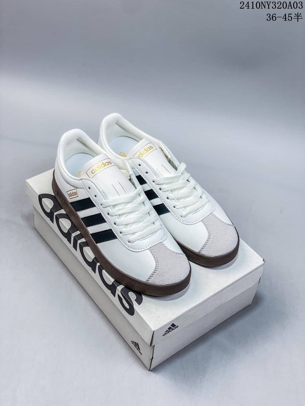 Pair of white Adidas Neo VL Court 2.0 sneakers with black side stripes, gray toe panels, and brown outsoles displayed on an Adidas shoe box.
