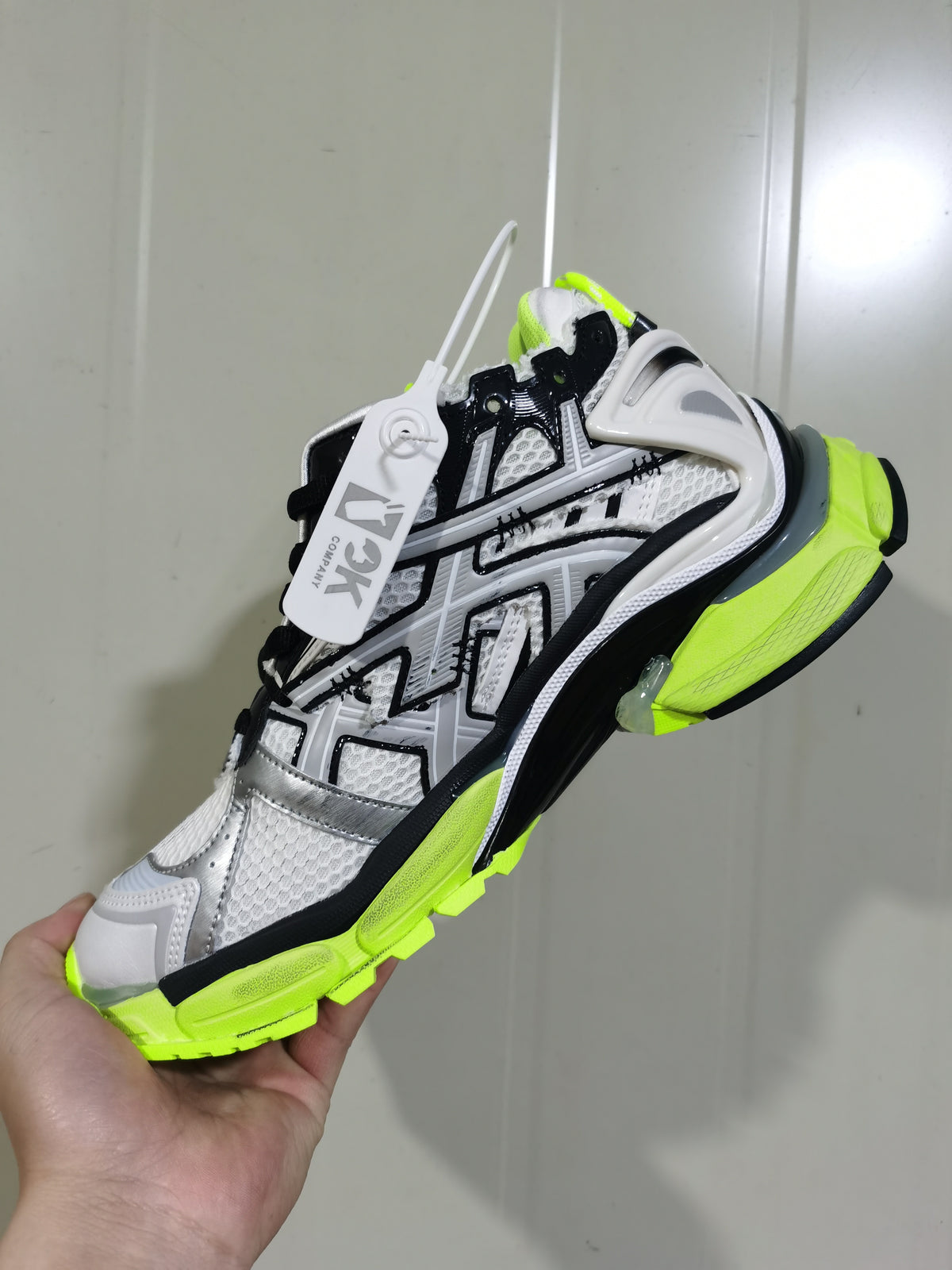 Angled view of white, black and neon yellow Balenciaga Runner-style sneakers with layered panels and a chunky outsole.