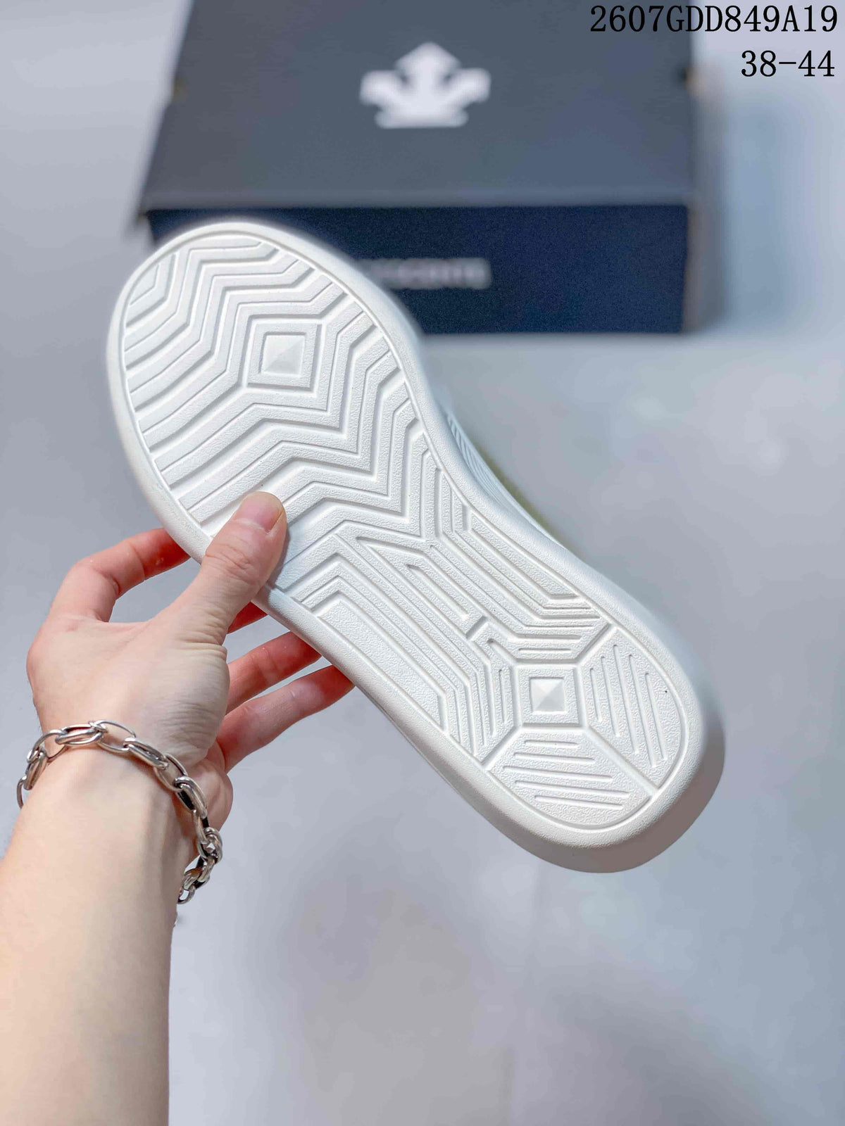 Close view of the white outsole showing a geometric tread pattern; style code 2607GDD849A19 and size range 38–44 appear in the background.