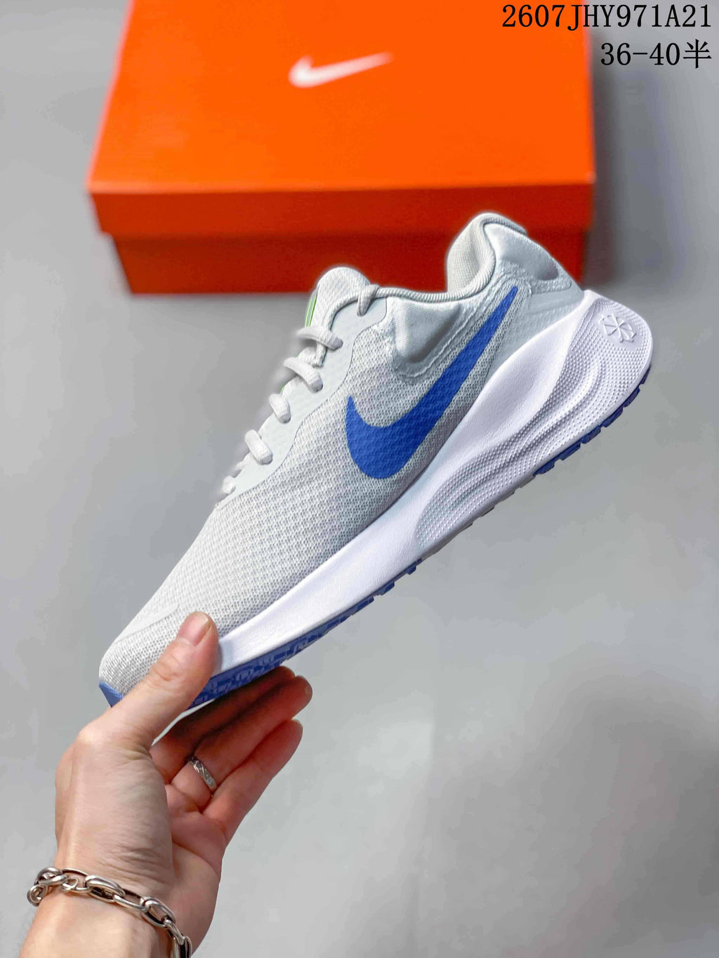 Side profile of a light gray Nike Vomero 18 running shoe with a blue Swoosh, white midsole, and blue outsole accents.