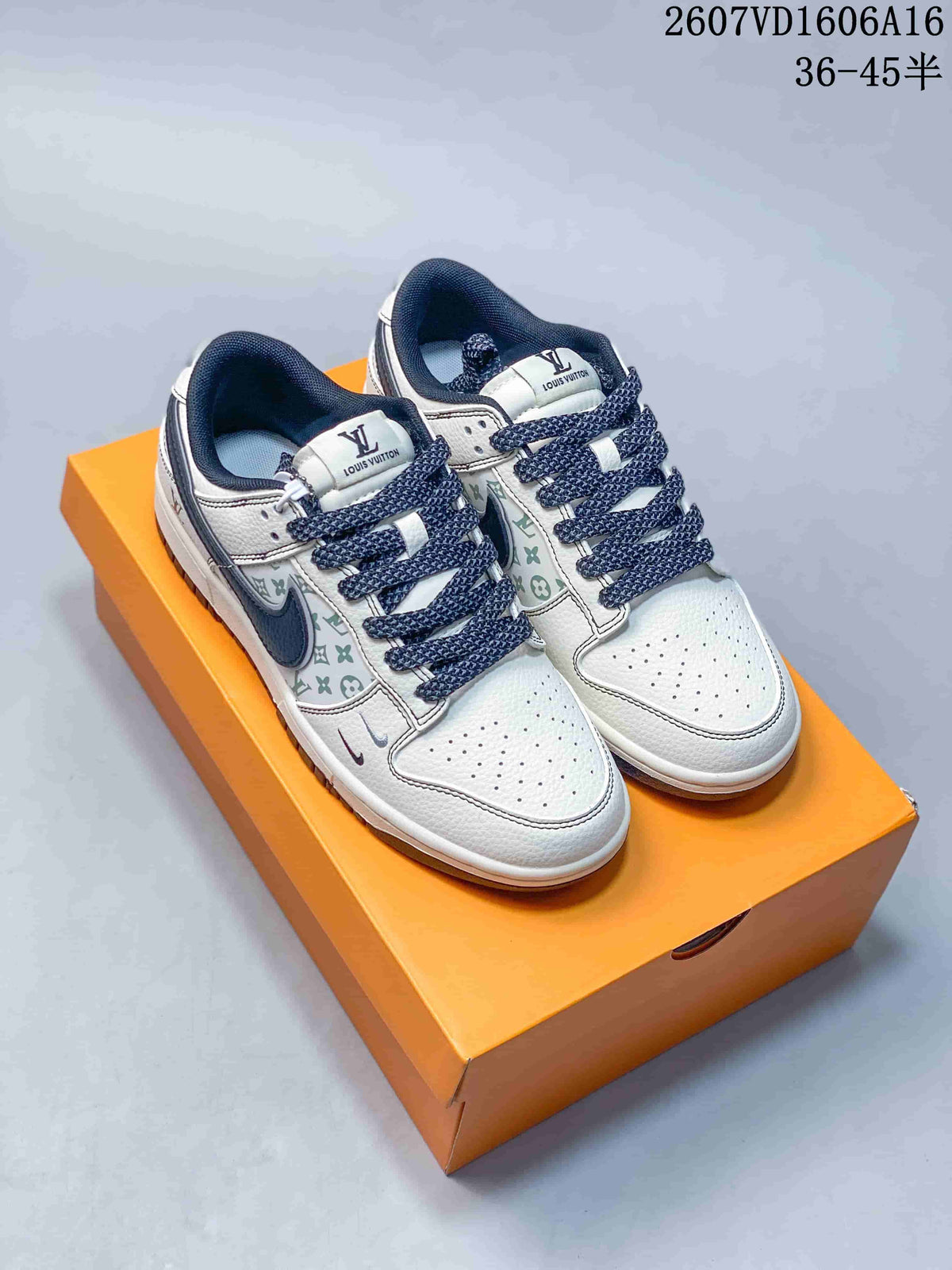 Pair of white sneakers with pale green and gray monogram-style side panels, dark navy collars, and dark navy laces on an orange shoe box.