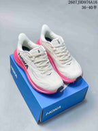 Pair of white and bright pink HOKA Clifton 10 sneakers displayed on a blue shoebox; image text shows style code 2607JHD976A16 and size range 36–40.5.
