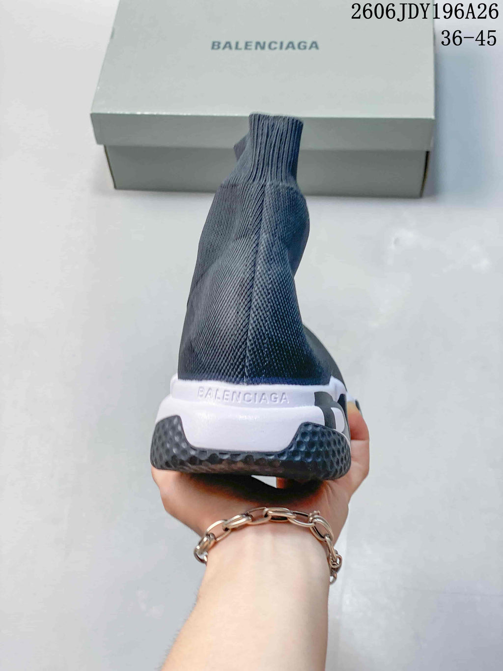 Rear view of a dark gray sock-style sneaker showing the ribbed ankle collar, white heel section, black outsole, and Balenciaga branding.