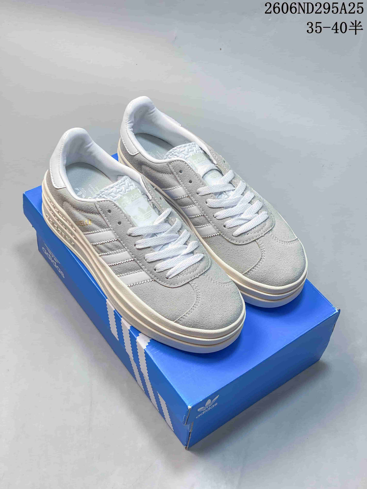 Pair of grey-and-white adidas Gazelle Bold low-top sneakers displayed on a blue adidas shoe box.