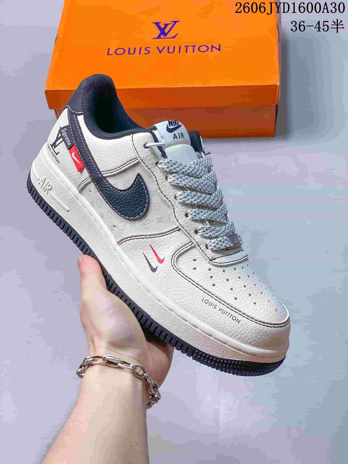 Cream low-top sneaker with dark swoosh and monogram-style side panels.