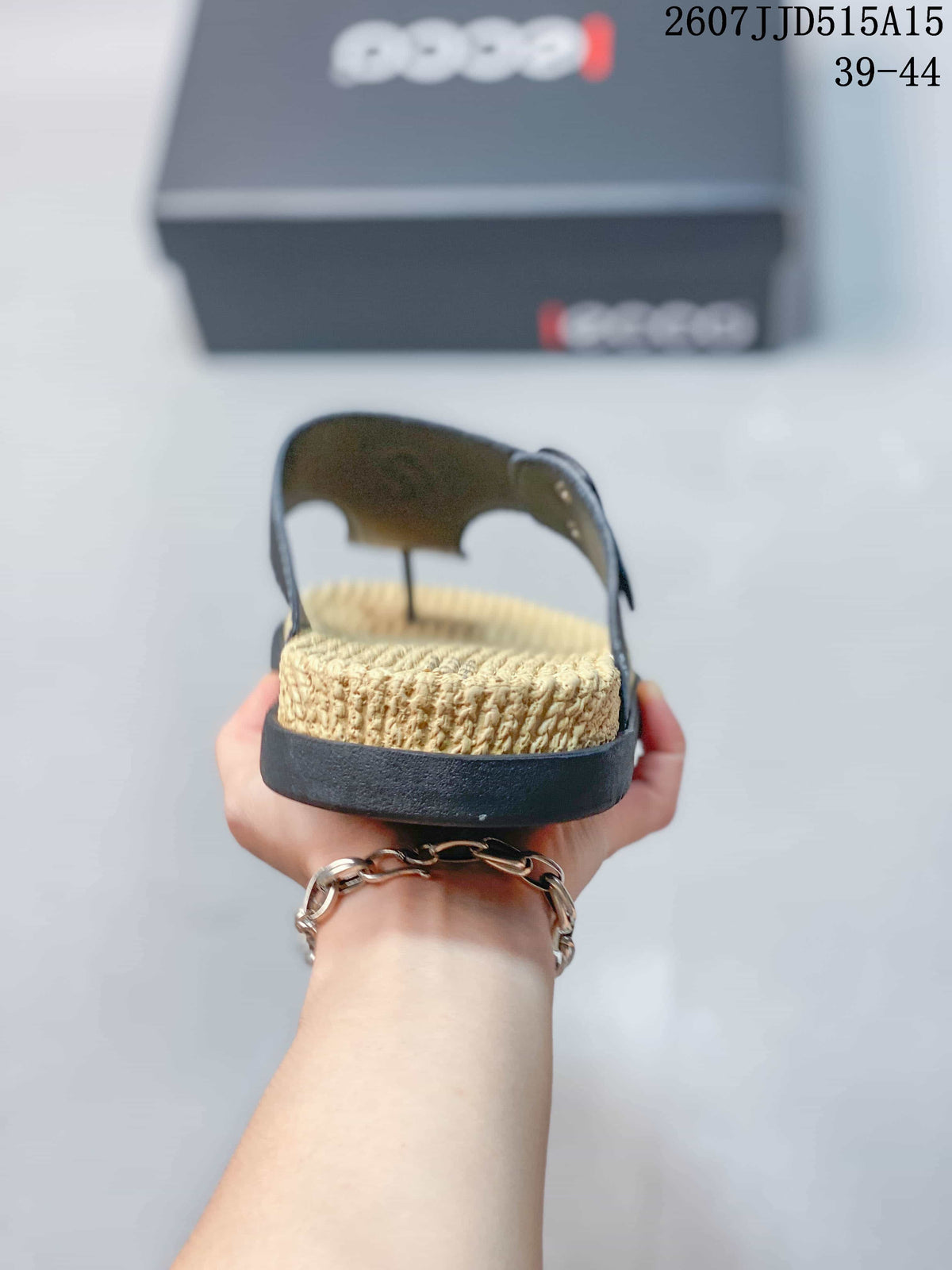 Rear view of a sandal showing the tan textured footbed, black outsole, and raised heel area.
