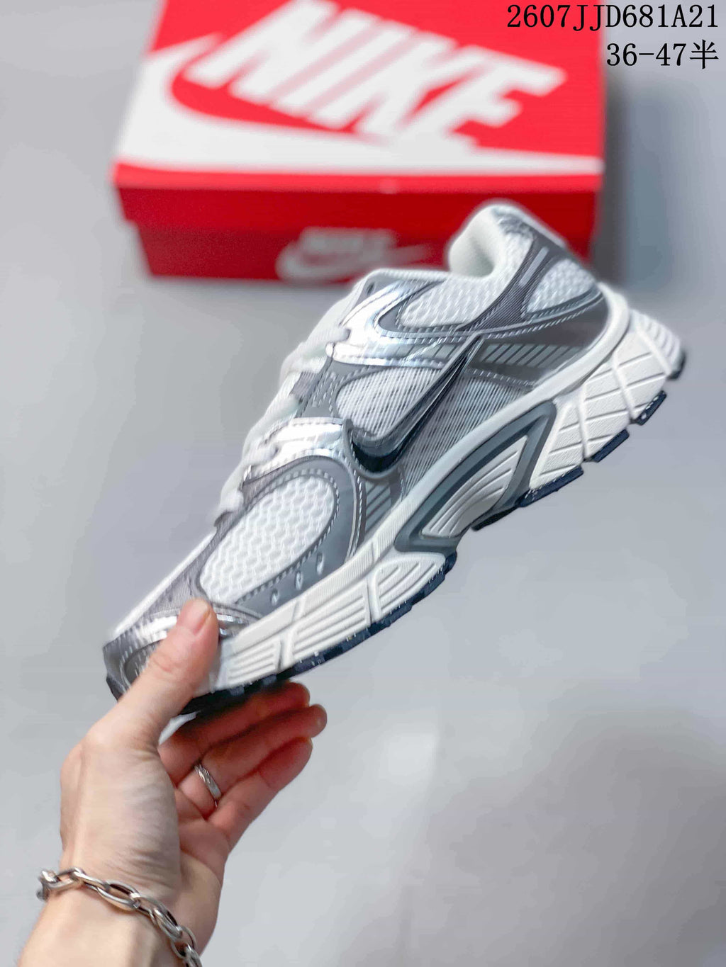 Side profile of a white and grey Nike V5 RNR sneaker showing the layered upper, Swoosh branding, and sculpted sole.