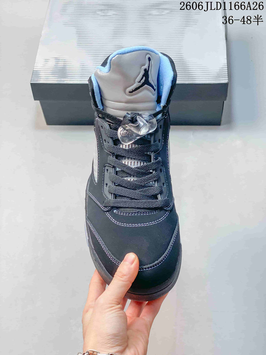 Front view of a dark high-top sneaker with light blue collar lining and lace toggle.