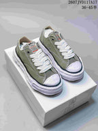 Pair of olive MMY low-top canvas sneakers with white laces, white toe caps and sculpted white soles.