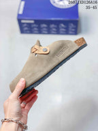 Side view of a taupe closed-toe mule with an adjustable buckle strap and visible BIRKENSTOCK marking.