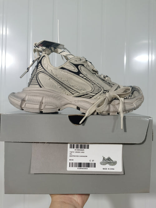 Beige and black 2002 sneakers displayed on their product box; the label shows size C 37 and identifies the color as beige.