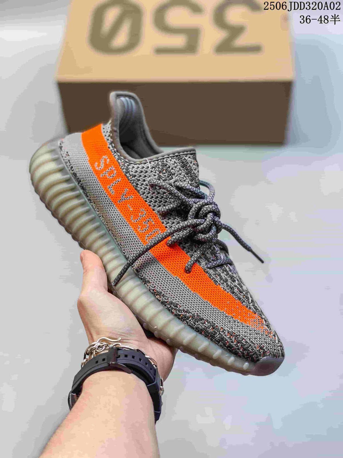 Angled side view of the grey Yeezy Boost 350 sneaker with a bright orange stripe and translucent sole.