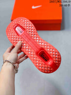 Close view of the bright red patterned outsole and orange Nike shoebox.