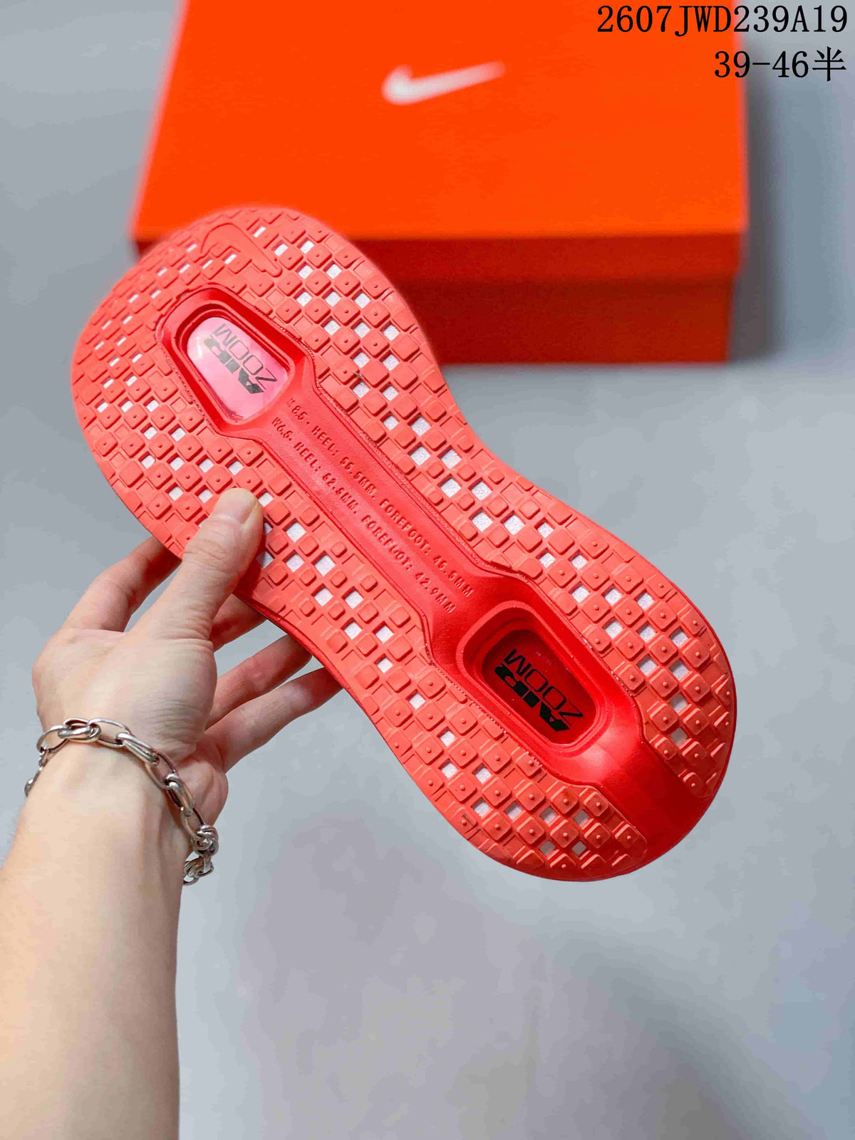 Close view of the bright red patterned outsole and orange Nike shoebox.