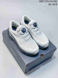 White Descente low-top running shoes with dark gray accents and dial closures, displayed on a box.