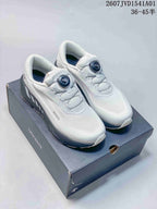 White Descente low-top running shoes with dark gray accents and dial closures, displayed on a box.