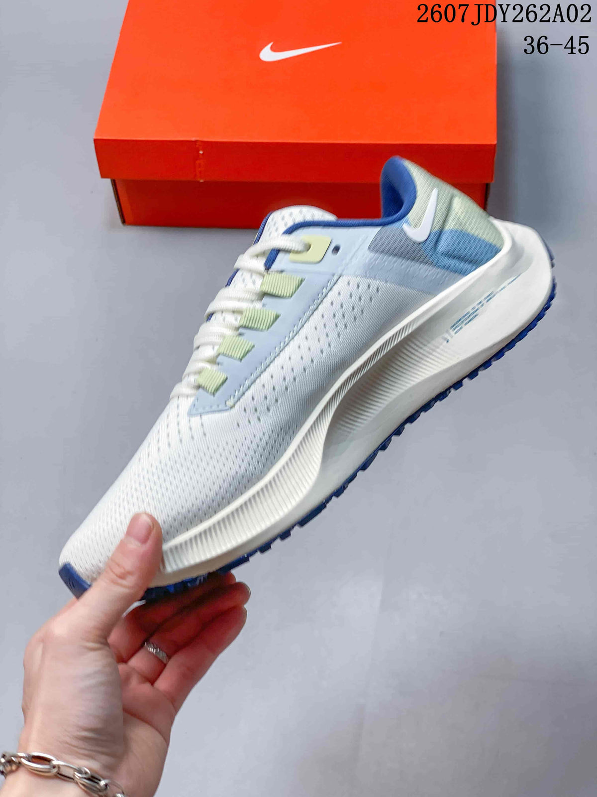 Side view of a Nike Pegasus 38 running shoe in off-white, pale blue and green.