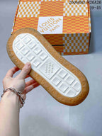 Underside of a sneaker showing a white tread center and gum-colored outsole, with a branded shoe box behind it.