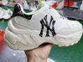 Close-up of an off-white chunky sneaker with a black NY logo pattern, black heel panel, patterned laces, and a sculpted textured outsole.