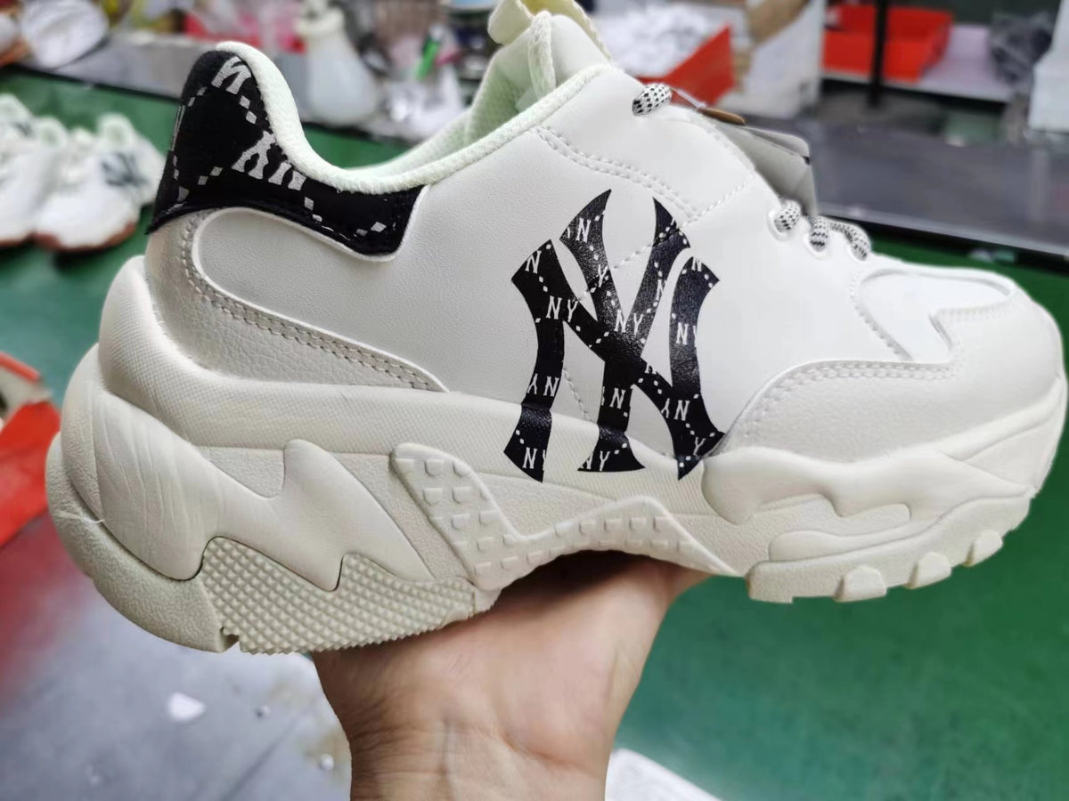 Close-up of an off-white chunky sneaker with a black NY logo pattern, black heel panel, patterned laces, and a sculpted textured outsole.