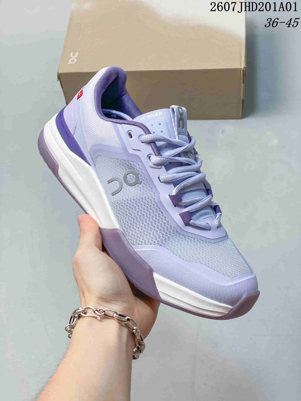 Angled side view of a light lavender and white On THE ROGER ADV Pro tennis shoe; image overlay shows code 2607JHD201A01 and sizes 36–45.