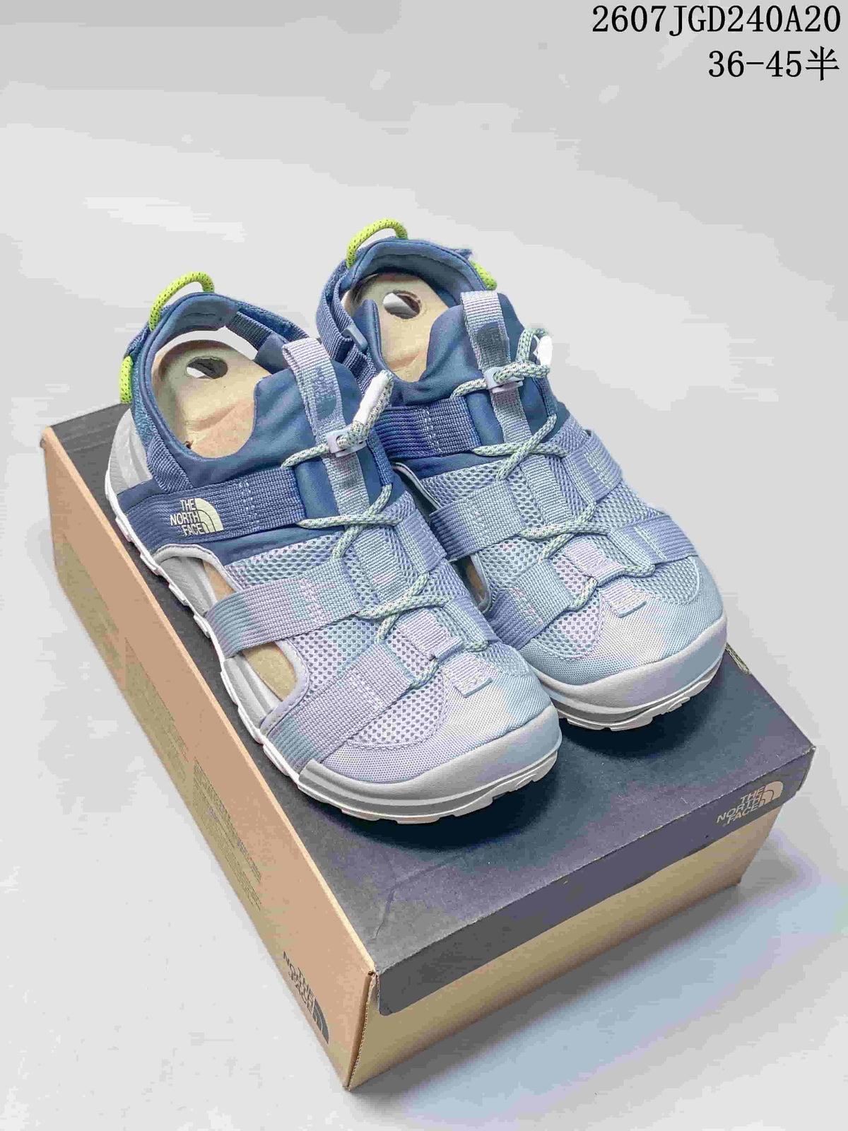 Blue The North Face Cedar Measa sandals displayed on a shoebox, with the product code and size range overlaid above.