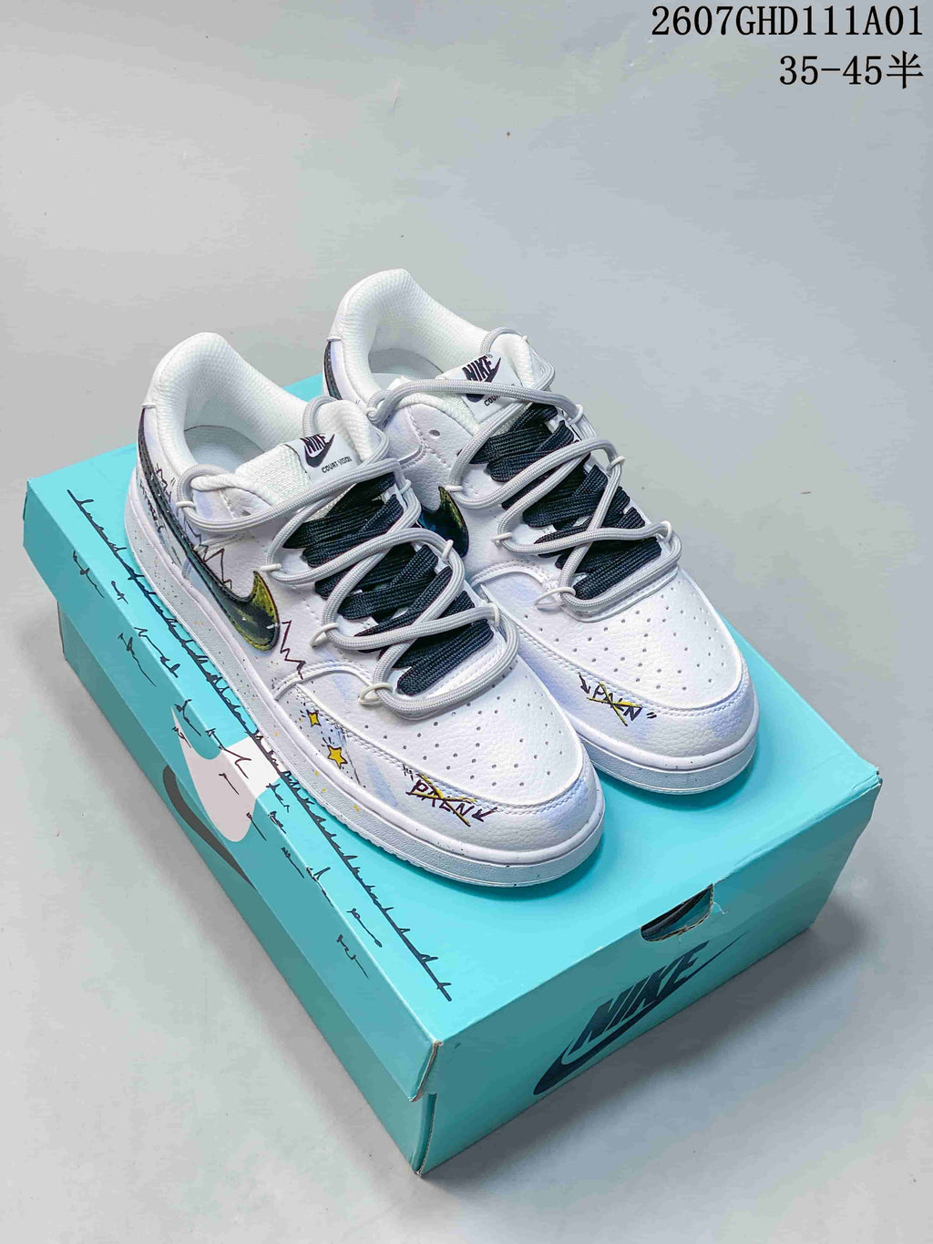 White Nike Court Vision low-top sneakers with colorful graphics and gray-and-dark laces on a turquoise box