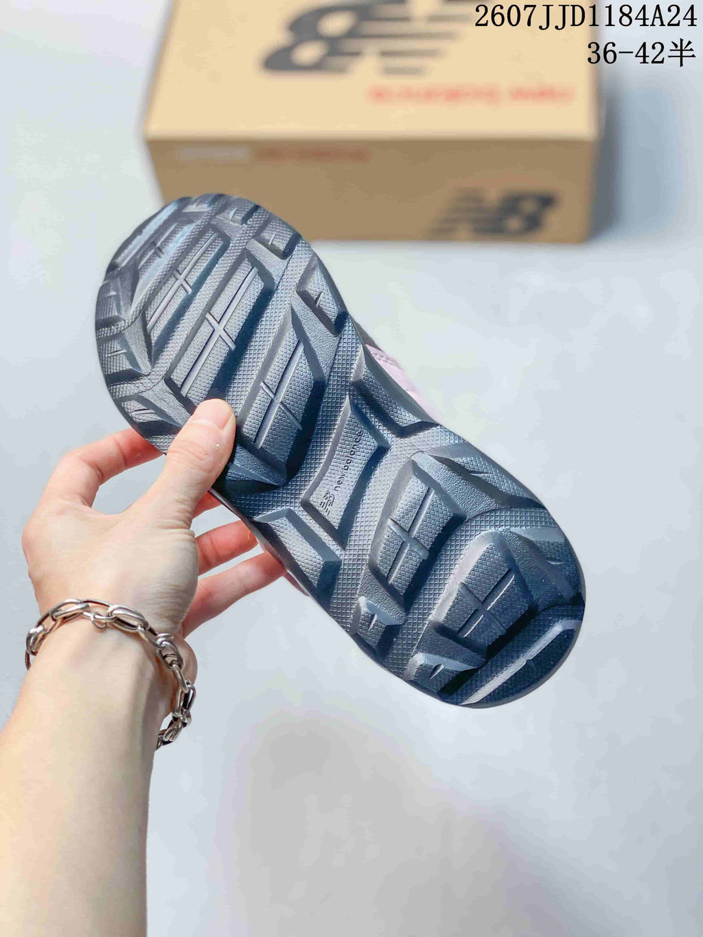 Close view of the dark outsole showing deep geometric tread sections and the New Balance logo.