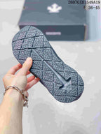 Underside of a black sneaker showing the geometric patterned outsole.